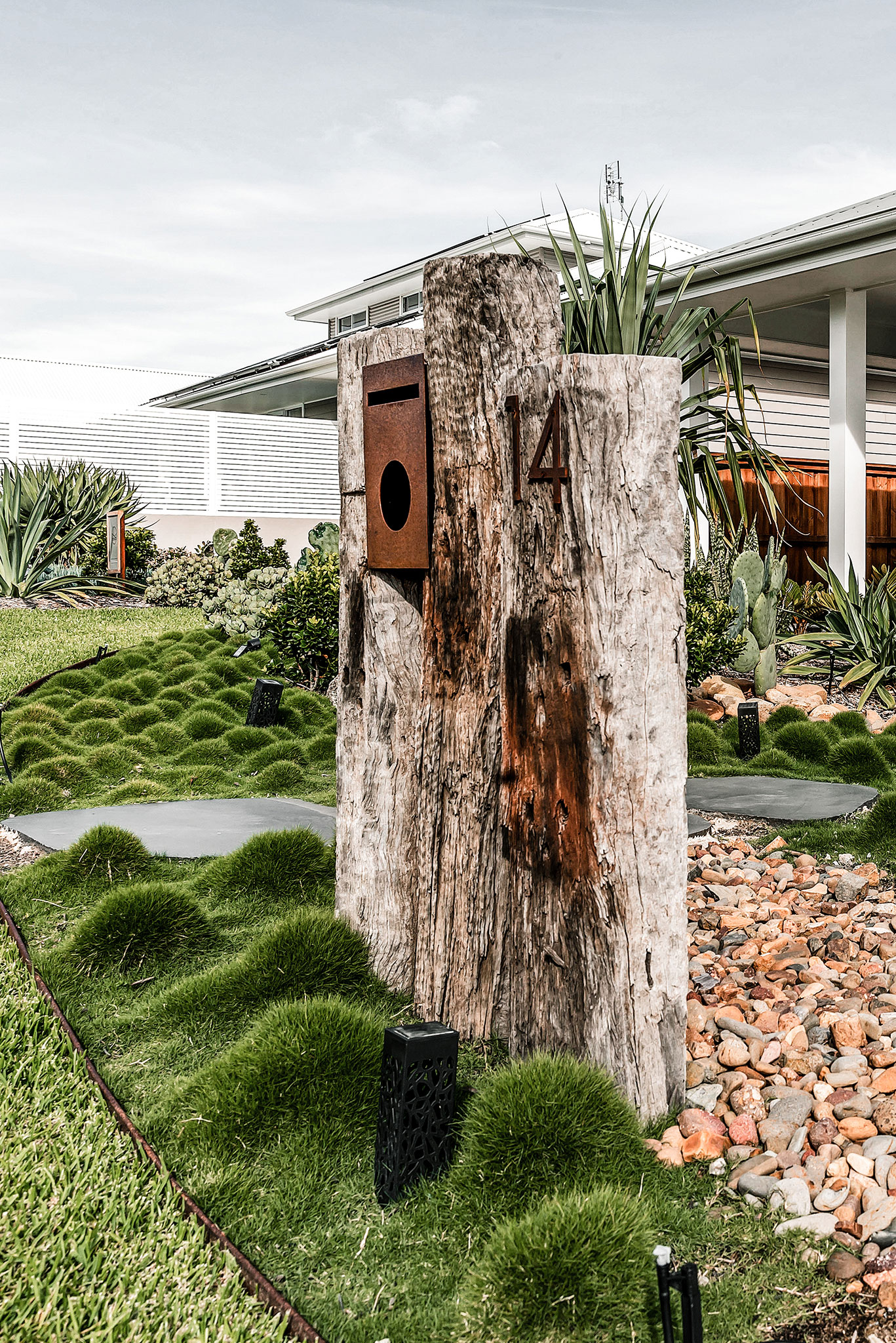 Custom recycled railway sleeper and Corten letterbox in garden bed with zoysia 'no mow' grass and bluestone stepping pavers