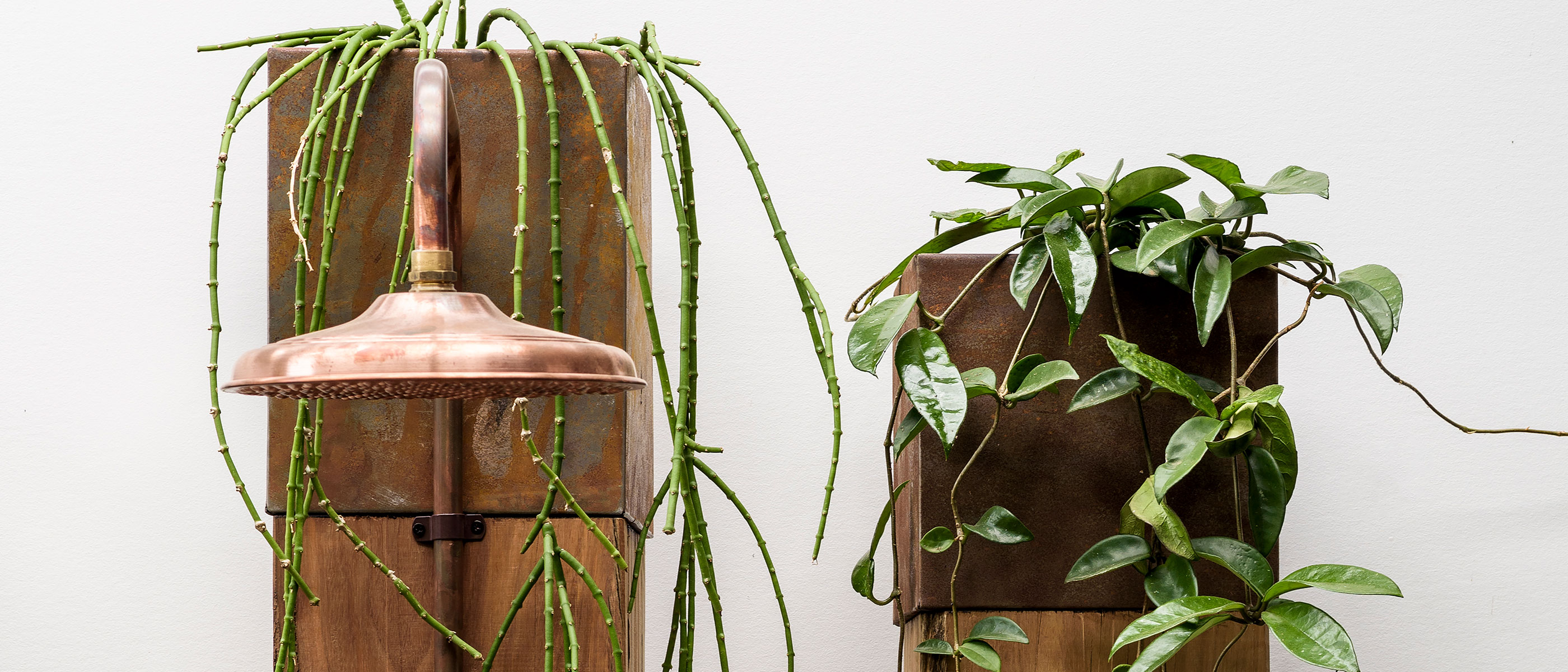 Custom recycled railway sleeper outdoor showers with copper fixtures and Corten planter boxes